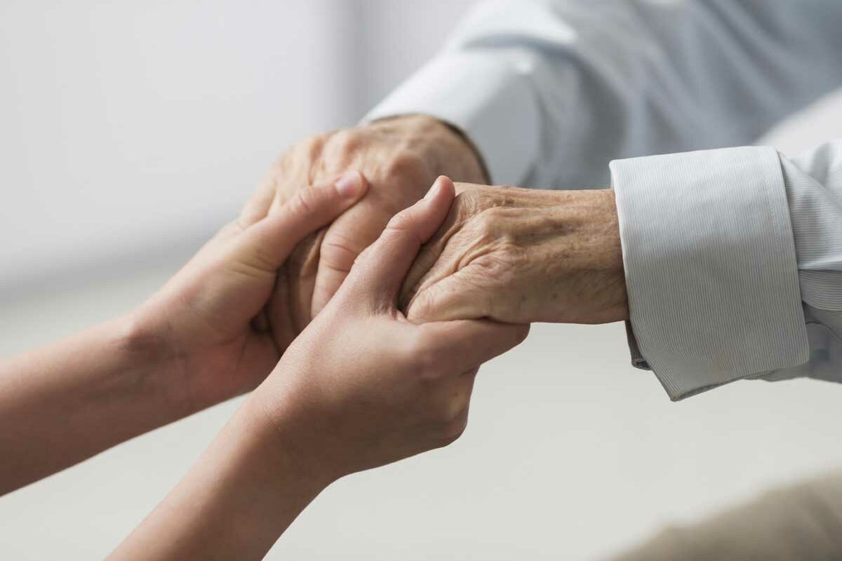 Une personne réconfortant un senior face au décès de sa femme. Il pourra prétendre à l'aide ASIR.