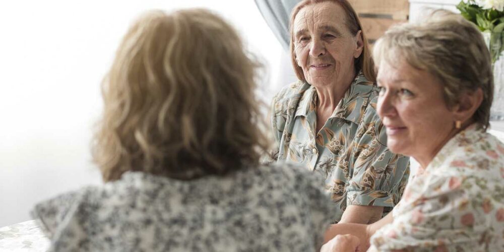 Une femme senior accompagnée de sa fille discute avec la gérante d'un hébergement temporaire