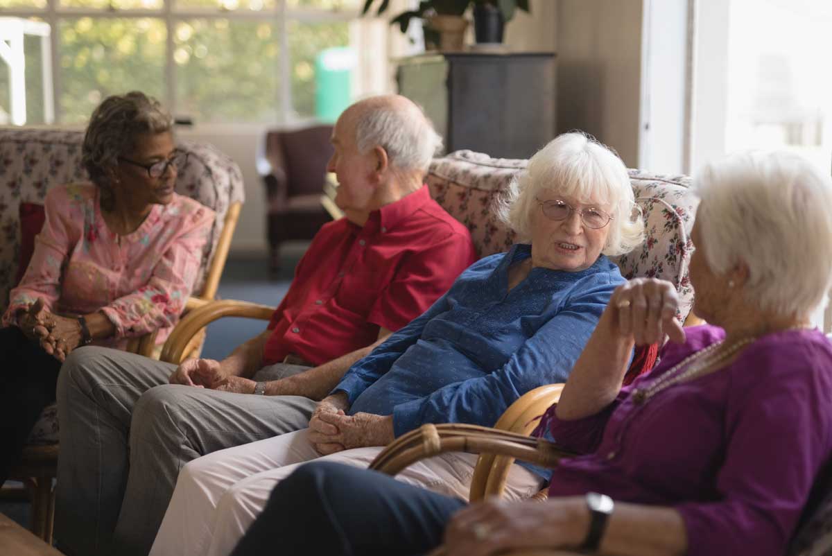 hebergement-temporaire1 Plusieurs personnes seniors discutent sur un canapé pendant leur hébergement temporaire en EHPAD