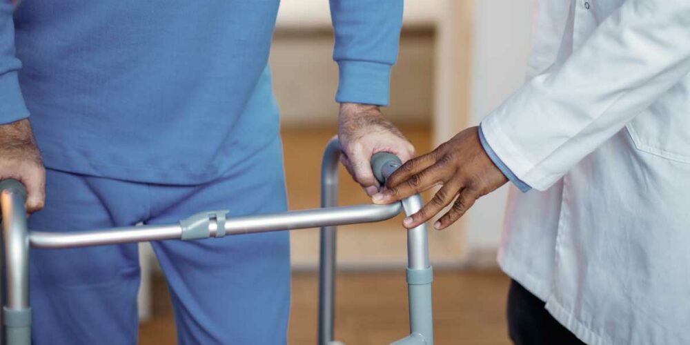 Un homme senior avec un déambulateur avec un soignant qui lui préconise le matériel médical le plus adapté