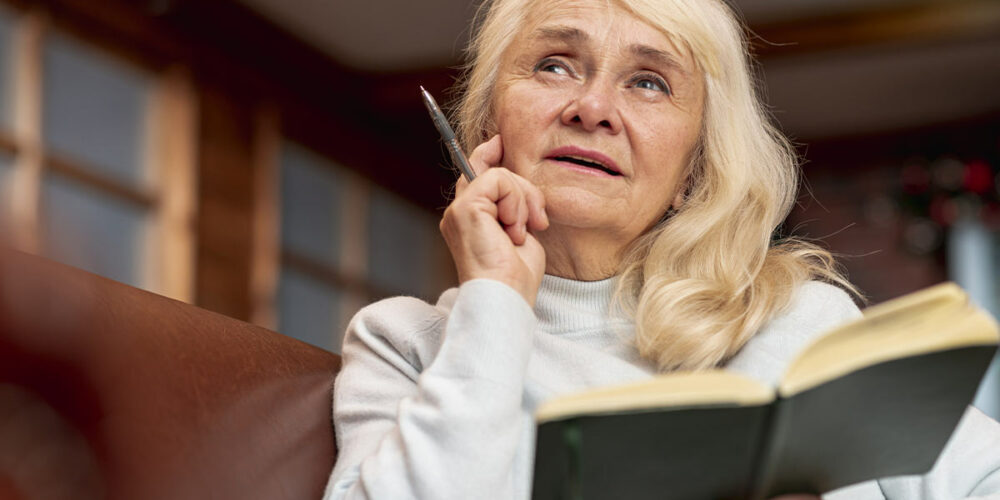 Femme qui pense avec un stylo et un carnet dans les mains