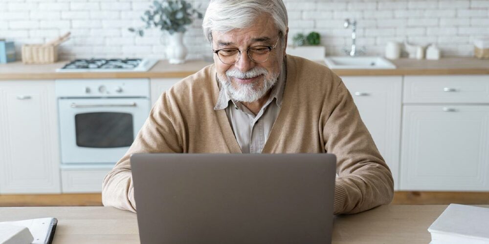 Senior qui garde le contact avec sa famille grâce aux aides informatiques