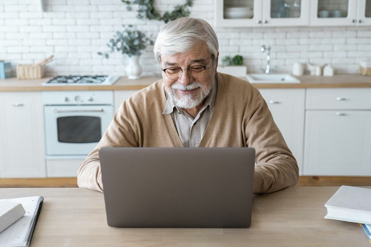 Senior qui garde le contact avec sa famille grâce aux aides informatiques