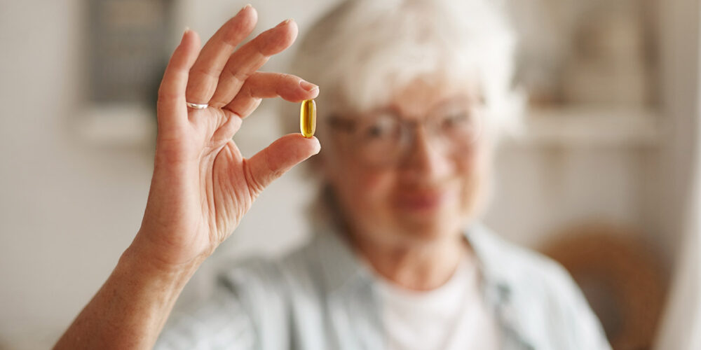 Femme qui tient dans sa main un complément alimentaire